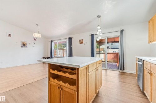 Open-concept living space featuring wood-finish flooring, a kitchen island with integrated wine storage, and light wood cabinetry - 16737 116 Street Nw, Edmonton, AB 