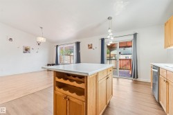 Open-concept living space featuring wood-finish flooring, a kitchen island with integrated wine storage, and light wood cabinetry - 