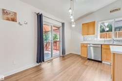 Kitchen area featuring wood-finish flooring, light wood cabinetry, and a stainless steel dishwasher - 