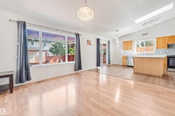 Open-concept living space featuring wood-finish flooring, a vaulted ceiling, and a prominent skylight - 