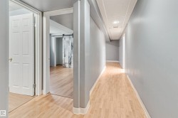 Hallway featuring wood-finish flooring, light gray wall paint, white baseboards, and overhead recessed lighting - 
