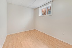 Wood-finish flooring throughout a neutral-toned room with a drop ceiling - 