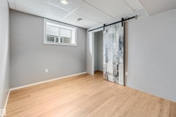 Room featuring wood-finish flooring, a white window frame, and a rustic barn door with black hardware - 