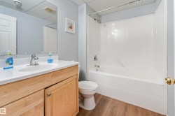 Bathroom featuring a light wood-finish vanity with an integrated sink, polished chrome faucet, and a large wall-mounted mirror - 