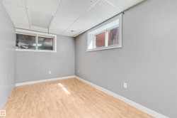 Finished room featuring wood-finish flooring, two windows, light gray walls, white trim, and a drop ceiling - 