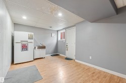 Finished lower level with wood-finish flooring, recessed lighting, and a utility sink with white cabinetry - 