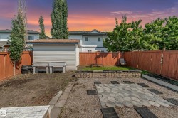 Spacious backyard featuring a utility shed, a paver patio area, and mature trees - 