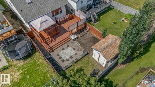 Multi-level rear deck with wood railing, featuring a lower patio with decorative pavers, and a detached shed with shingle roofing - 16737 116 Street Nw, Edmonton, AB 