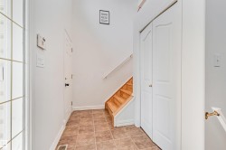 Foyer featuring ceramic tile flooring, a staircase with wood treads and white risers, and two white panel doors - 