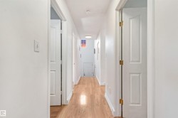 Bright hallway featuring light wood-finish flooring and white walls - 