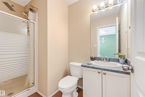 Bathroom featuring a shower with frosted glass enclosure, white vanity with blue countertop, oval drop-in sink, and a mirrored medicine cabinet with vanity lighting - 16737 116 Street Nw, Edmonton, AB 