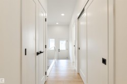 Hallway with light wood-finish flooring, white walls, and recessed lighting - 