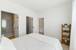 Bedroom with light wood-finish flooring and white walls - 
