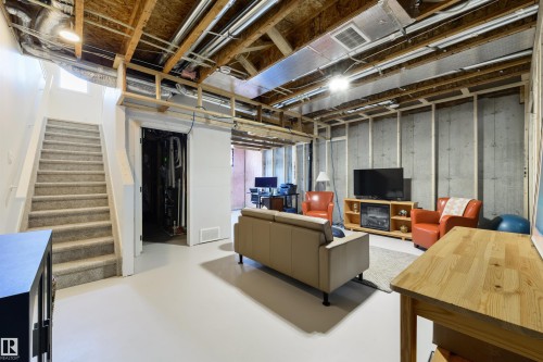Open lower level featuring a light gray finished floor, exposed wood ceiling joists, and concrete foundation walls with wood framing - 323 Rankin Drive, St. Albert, AB - Indoor Photo Showing Basement