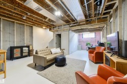 Spacious unfinished basement offering concrete foundation walls, exposed overhead joists, and a painted concrete floor - 