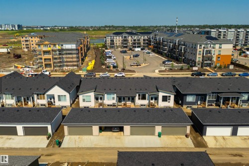 Aerial perspective showcasing multiple properties including detached garages with dark sectional doors, a row of townhouses with dark shingled roofs, and multi-story apartment buildings with balconies - 323 Rankin Drive, St. Albert, AB - Outdoor With View