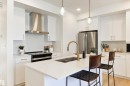 Contemporary kitchen featuring a central island with an undermount sink and brass faucet, white cabinetry, integrated stainless steel appliances, and pendant lighting - 323 Rankin Drive, St. Albert, AB  - Indoor Photo Showing Kitchen With Double Sink With Upgraded Kitchen 