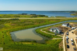 Newly constructed property featuring a modern architectural design, situated alongside a water retention pond and walking path - 