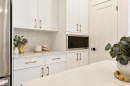 Modern kitchen featuring white cabinetry with gold-tone hardware, a stainless steel built-in microwave, and light-colored countertops - 323 Rankin Drive, St. Albert, AB  - Indoor 