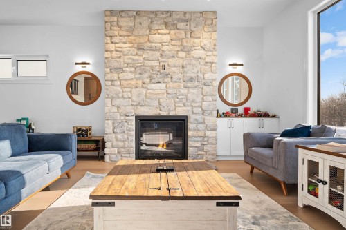 Stone-faced fireplace with a glass front insert - 12304 62 Ave Nw, Edmonton, AB - Indoor Photo Showing Living Room With Fireplace