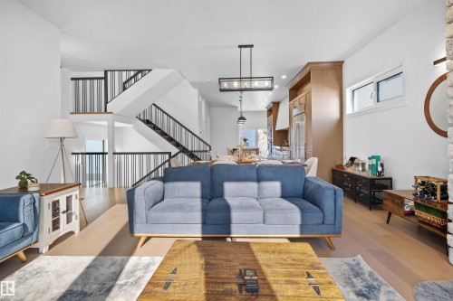 Open-concept living area featuring wood-finish flooring, a modern staircase with black metal railings, and recessed lighting - 12304 62 Ave Nw, Edmonton, AB - Indoor