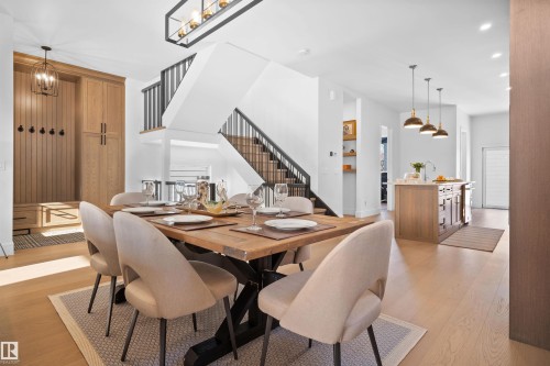 Open-concept dining space with light wood-finish flooring, featuring a large dining table and six upholstered chairs - 12304 62 Ave Nw, Edmonton, AB - Indoor Photo Showing Dining Room