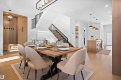 Open-concept dining space with light wood-finish flooring, featuring a large dining table and six upholstered chairs - 