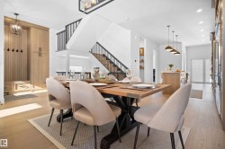Bright dining area featuring wood-finish flooring, a contemporary staircase with dark railings, a built-in wood-finish hall tree with cabinetry, and recessed lighting - 