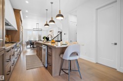 Open-concept kitchen featuring light wood-finish cabinetry, stainless steel appliances, and a central island with a light-colored countertop - 