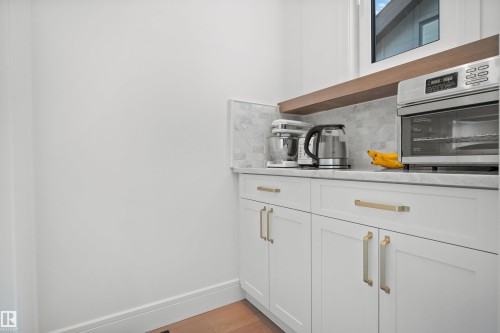 White cabinetry featuring brushed gold hardware, a light-toned countertop, and a matching full-height backsplash - 12304 62 Ave Nw, Edmonton, AB - Indoor Photo Showing Other Room