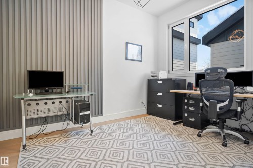 Bright room featuring a large window, light wood-finish flooring, and a textured accent wall with vertical paneling - 12304 62 Ave Nw, Edmonton, AB - Indoor Photo Showing Other Room