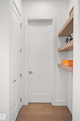 White interior door with brushed nickel hardware, flanked by a second white door and built-in floating shelves - 12304 62 Ave Nw, Edmonton, AB - Indoor Photo Showing Other Room