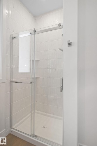Enclosed shower stall featuring clear glass sliding doors and a white subway tile surround - 12304 62 Ave Nw, Edmonton, AB - Indoor Photo Showing Bathroom