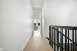 Hallway featuring light wood-finish flooring, white baseboards, and recessed lighting - 