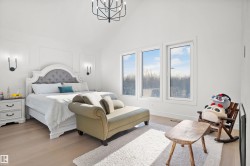 Vaulted ceiling with a contemporary chandelier, light wood-finish flooring, and three large windows - 