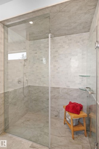 Walk-in shower featuring a frameless glass enclosure, a handheld showerhead, two-tone tile walls, and a recessed ceiling light - 12304 62 Ave Nw, Edmonton, AB - Indoor Photo Showing Bathroom
