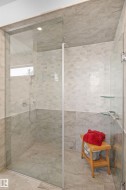Walk-in shower featuring a frameless glass enclosure, a handheld showerhead, two-tone tile walls, and a recessed ceiling light - 