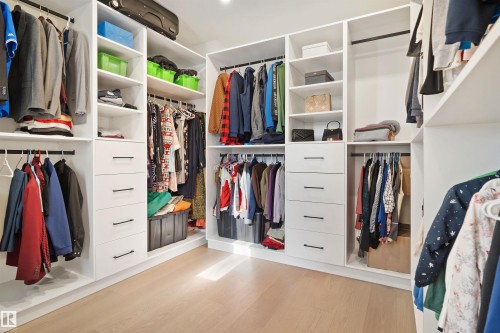 Custom closet system featuring multiple hanging rods, integrated shelving, and drawers with dark hardware - 12304 62 Ave Nw, Edmonton, AB - Indoor With Storage