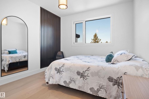 Light-toned wood-finish flooring complements the white walls and modern overhead lighting fixture - 12304 62 Ave Nw, Edmonton, AB - Indoor Photo Showing Bedroom