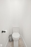White toilet set against light gray walls with a matte black toilet paper holder and light-colored stone-look flooring - 
