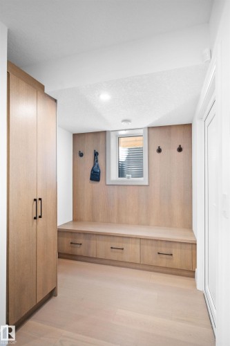 Built-in wood-finish bench with integrated storage drawers, complemented by tall wood-finish cabinetry and light wood-finish flooring - 12304 62 Ave Nw, Edmonton, AB - Indoor Photo Showing Other Room