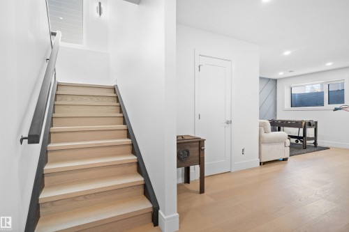 Hardwood stairs with a dark handrail, overhead recessed lighting, and a window providing natural illumination - 12304 62 Ave Nw, Edmonton, AB - Indoor Photo Showing Other Room
