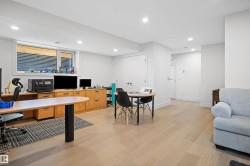 Spacious room featuring light wood-finish flooring, recessed lighting, and a large egress window with horizontal blinds - 