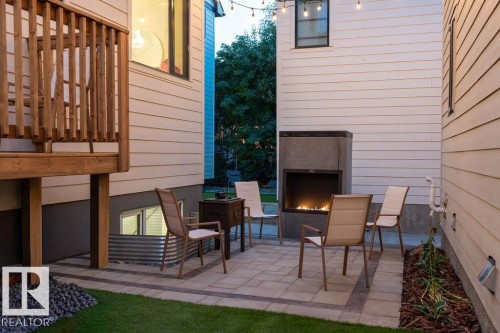 Outdoor patio featuring a built-in fireplace, string lighting, and paver stone flooring - 12304 62 Ave Nw, Edmonton, AB - Outdoor With Exterior