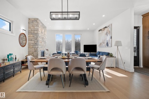 Open-concept living space featuring light wood-finish flooring, recessed lighting, a stone-clad fireplace, and large windows - 12304 62 Ave Nw, Edmonton, AB - Indoor Photo Showing Dining Room