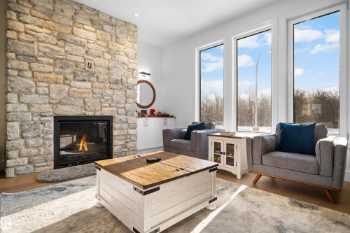 Stone veneer fireplace with an integrated firebox, accompanied by built-in white cabinetry - 12304 62 Ave Nw, Edmonton, AB - Indoor Photo Showing Living Room With Fireplace