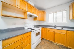Kitchen featuring wood-finish cabinetry, solid surface countertops, a stainless steel double basin sink, and a white electric range with an overhead vent - 