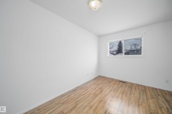 Room featuring wood-finish flooring, a single window, white walls, and a ceiling-mounted light fixture - 