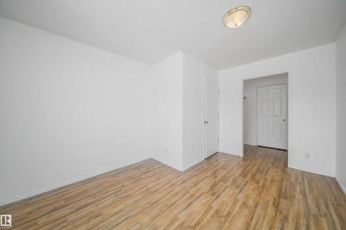 Open room featuring wood-finish flooring, white walls, and a flush-mount ceiling light fixture - 12041/43 67 St Nw Nw, Edmonton, AB - Indoor Photo Showing Other Room
