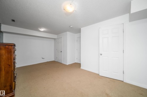Carpeted room with white walls, white trim, and two white panel doors - 12041/43 67 St Nw Nw, Edmonton, AB - Indoor Photo Showing Other Room